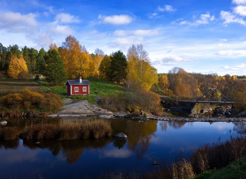 Rotes Holzhaus an Finnischem See im Herbst