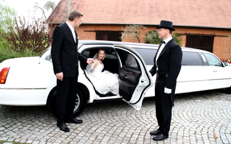 Braut steigt aus Lincoln Town Car Stretchlimousine aus