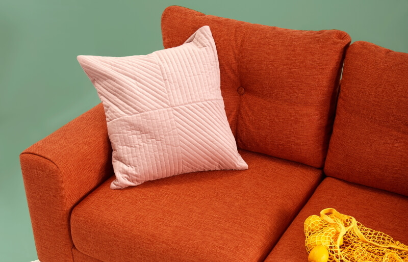 Orange farbenes Sofa vor grüner Wand