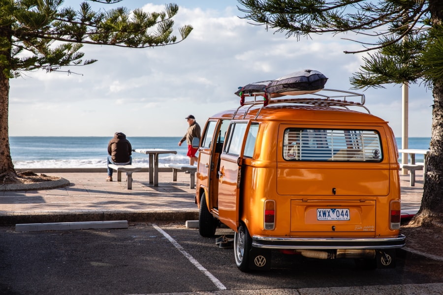 Orangener VW Campingbus am Strand