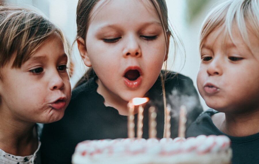 Kinder pusten Kerze auf Kuchen aus
