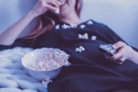 Frau isst Popcorn auf Sofa
