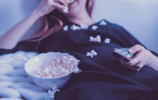 Frau isst Popcorn auf Sofa