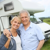 Seniorenpaar vor Wohnmobil im Urlaub
